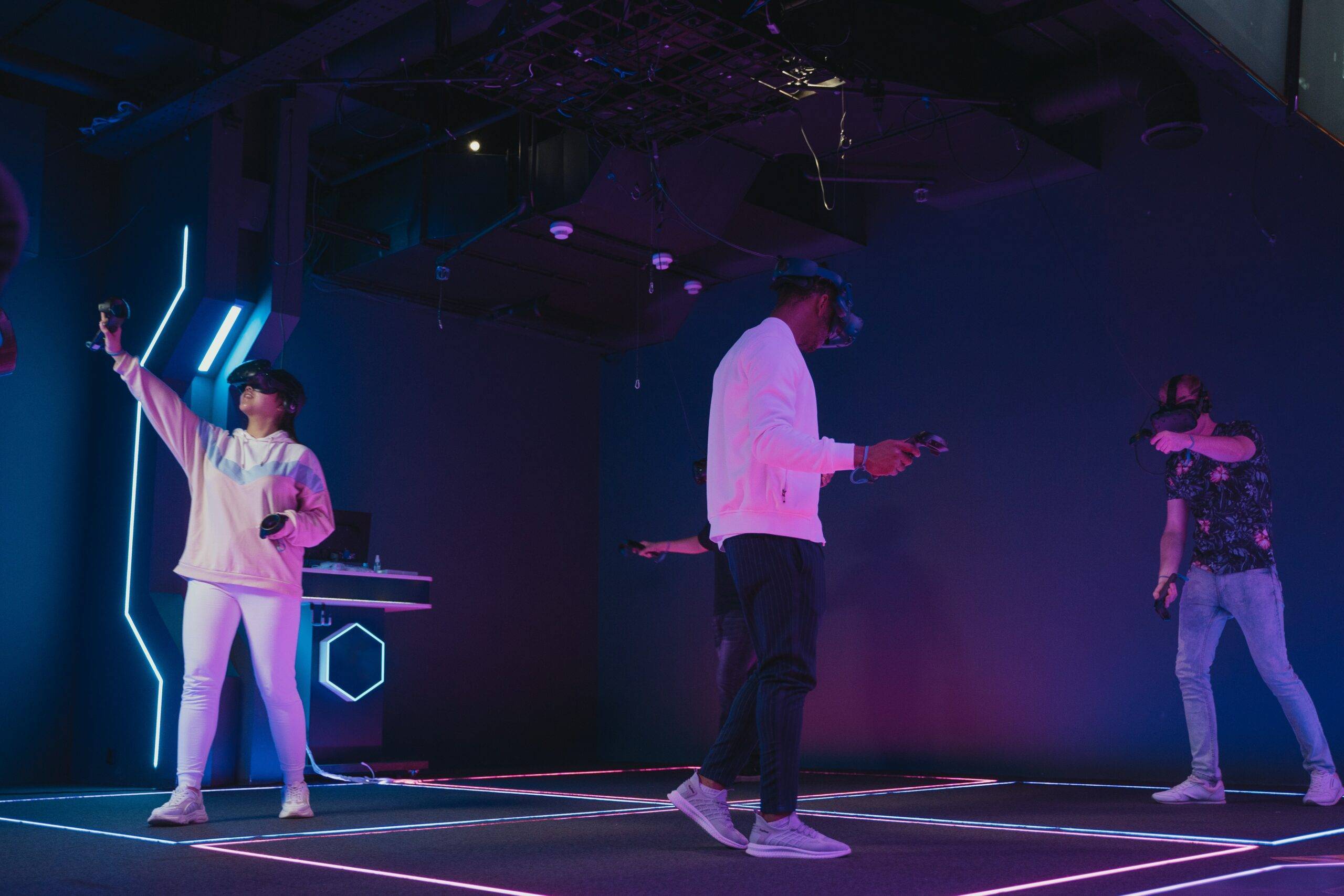 Three teenagers in a virtual reality escape room, wearing headsets and holding controllers.